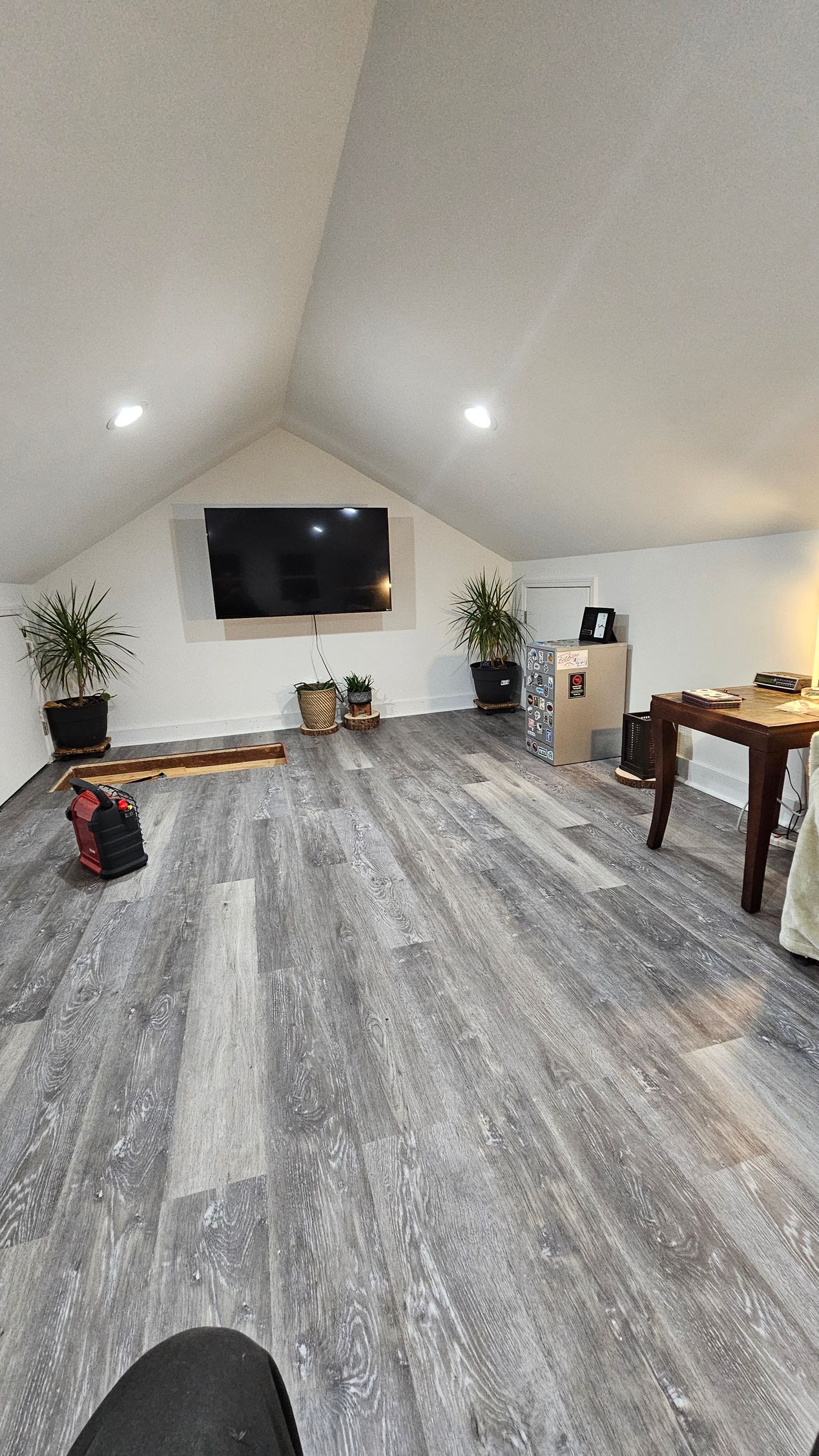 A living room with hardwood floors and a flat screen tv on the wall.