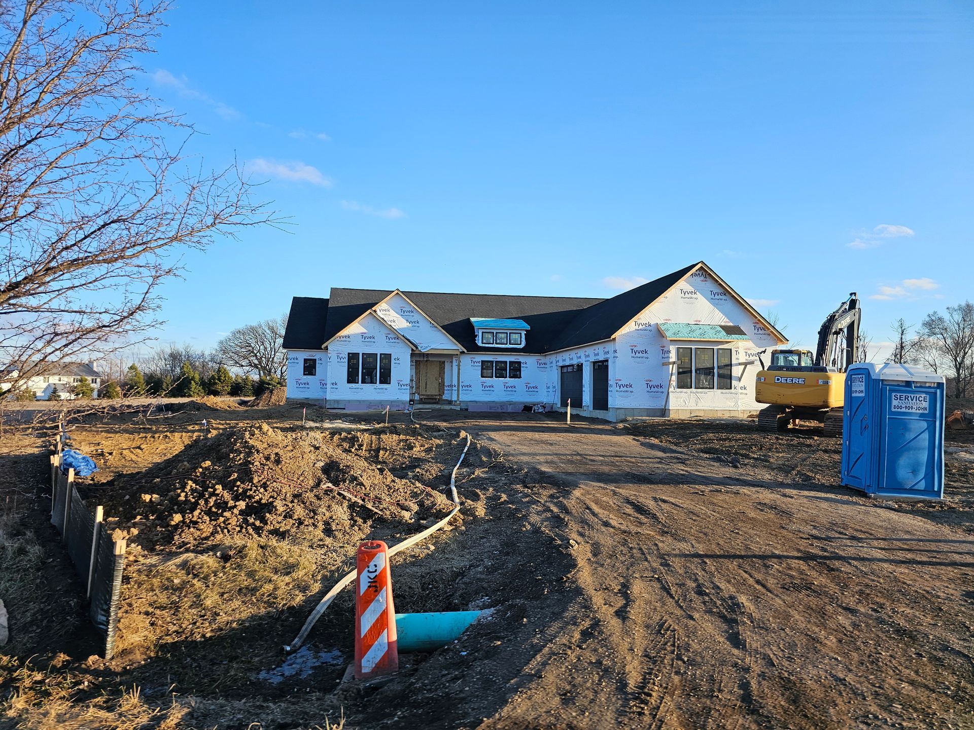 A large house is being built on a dirt road.