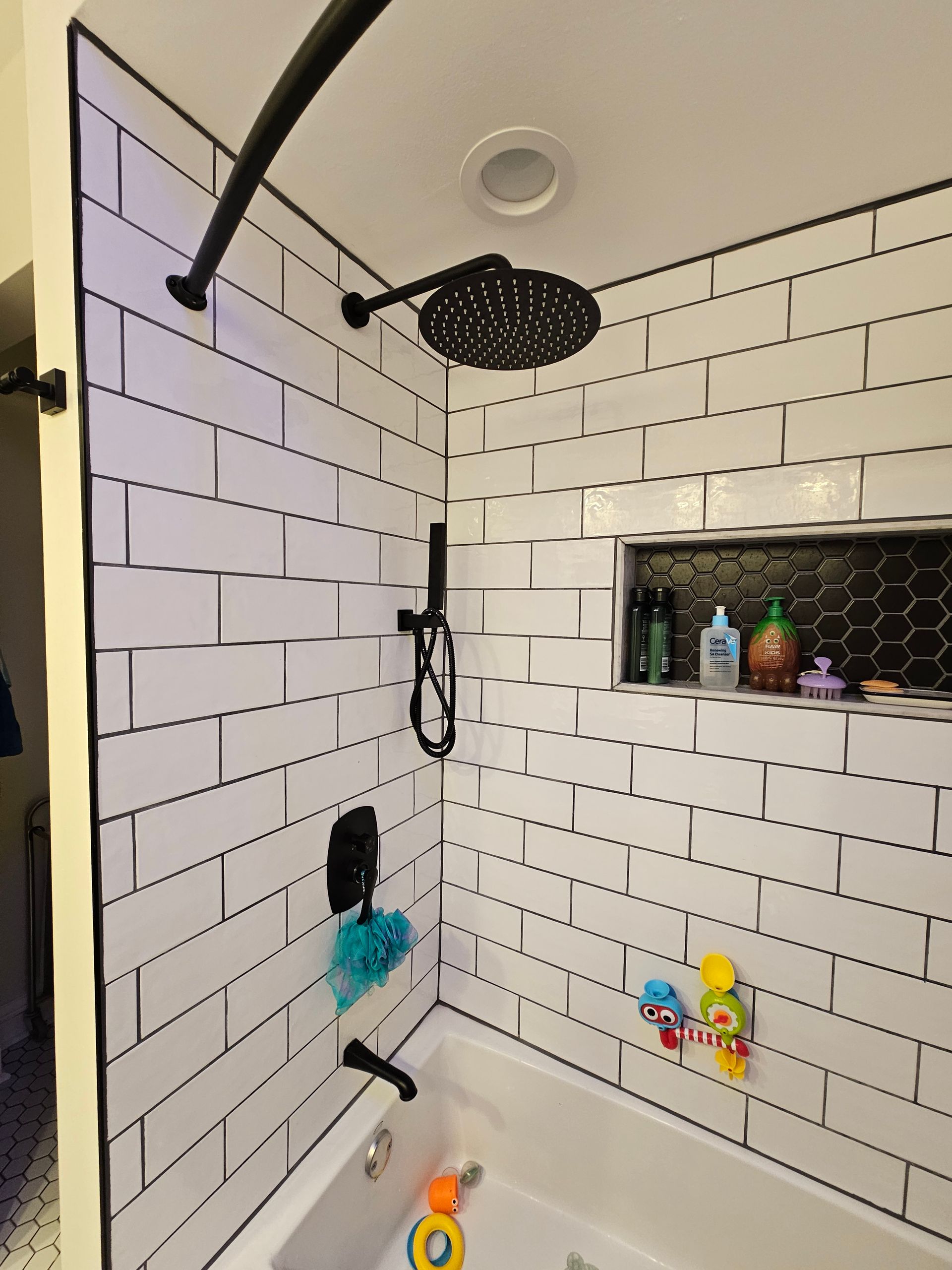 A bathroom with white brick walls , a tub and a shower head.