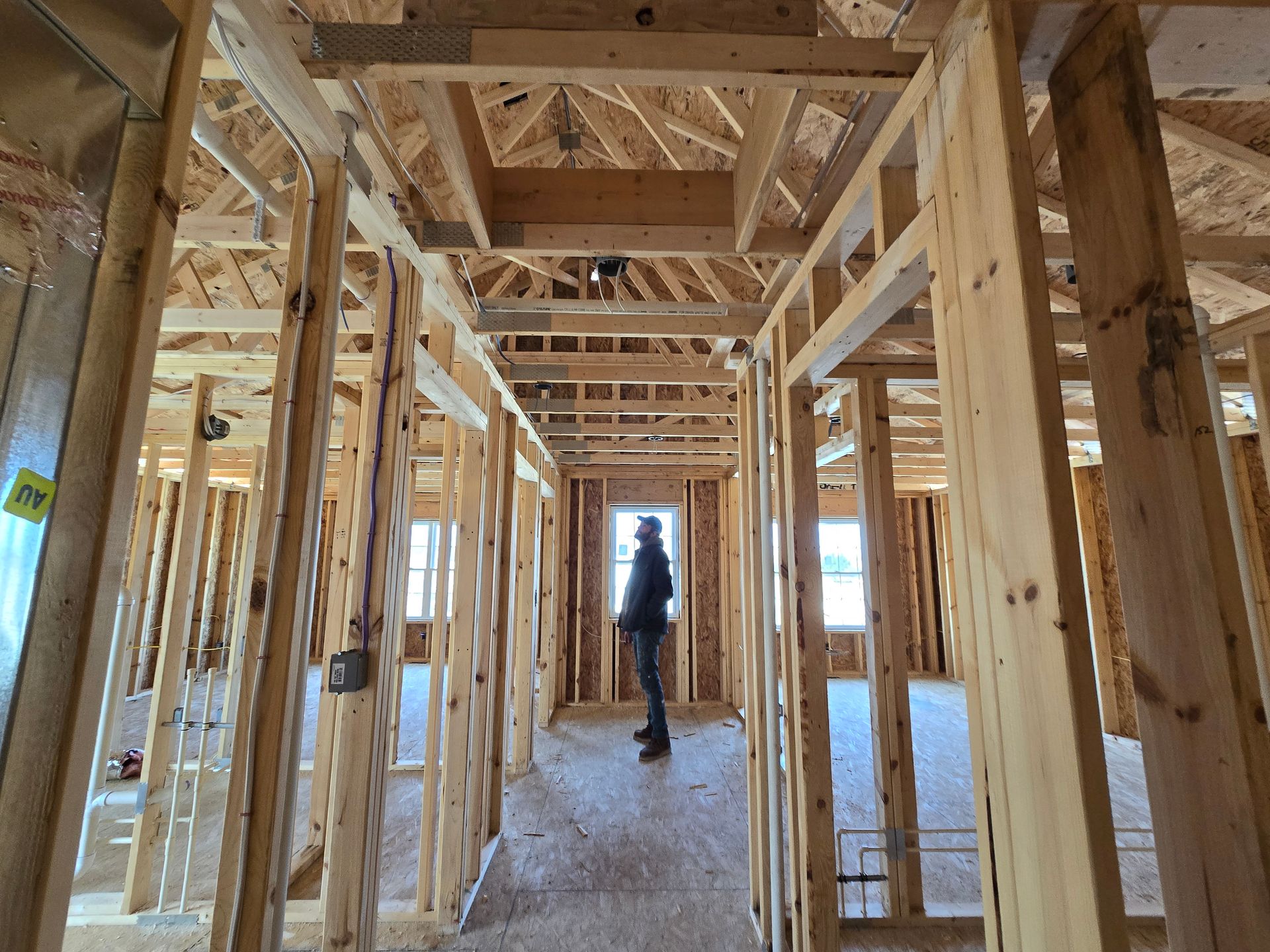A man is standing in the hallway of a house under construction.