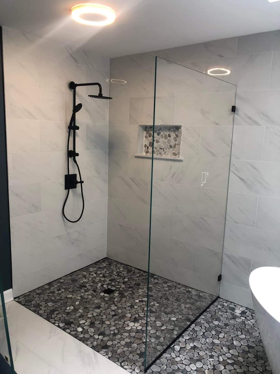 A bathroom with a walk in shower and a black shower head.