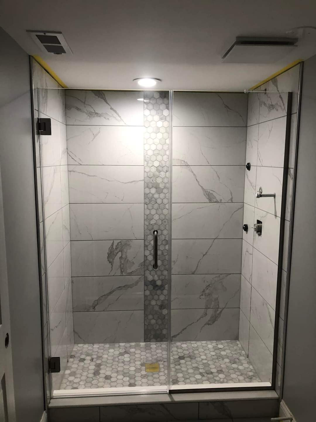 A bathroom with a walk in shower with a glass door.