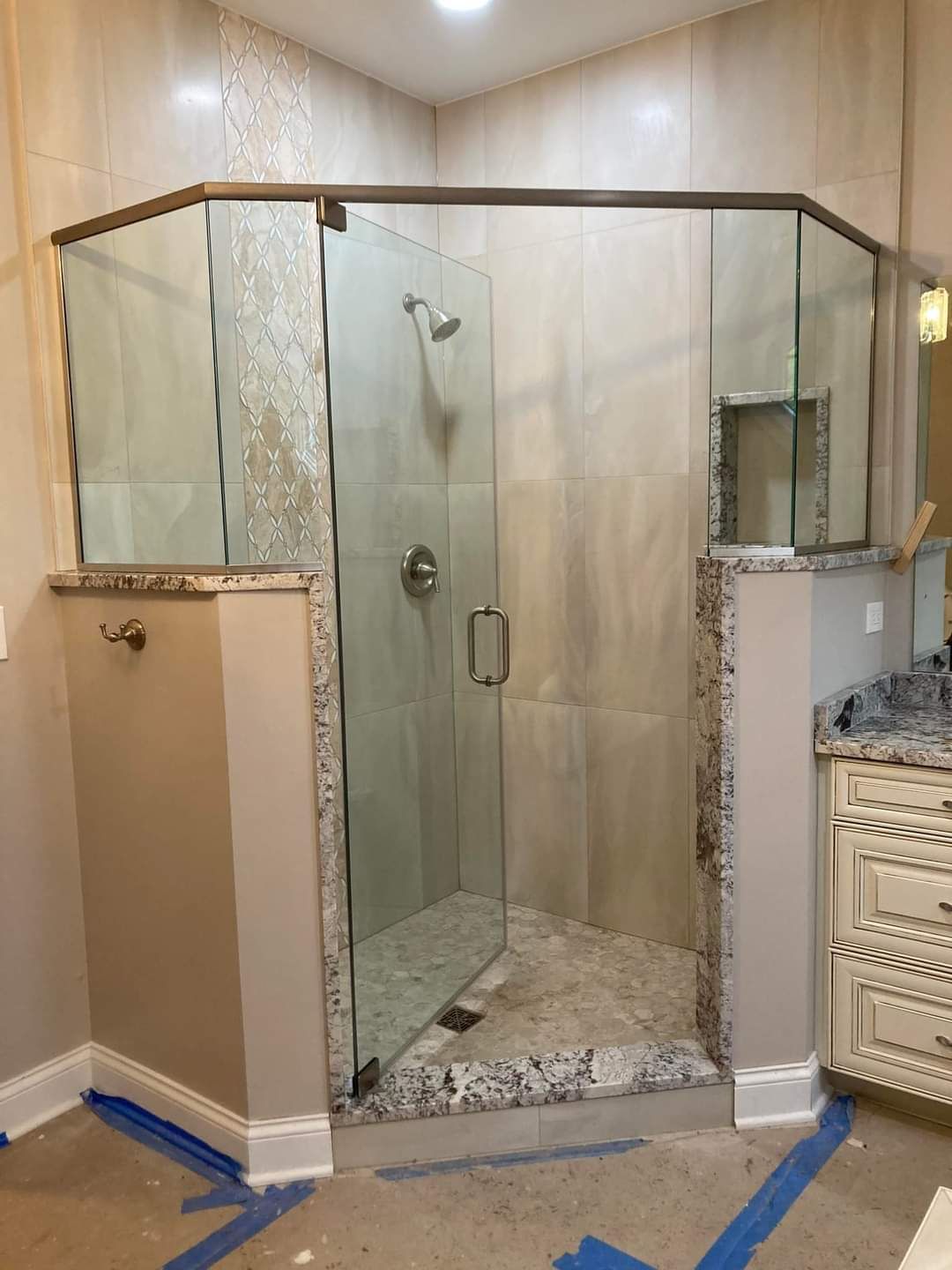A bathroom with a walk in shower with a glass door.