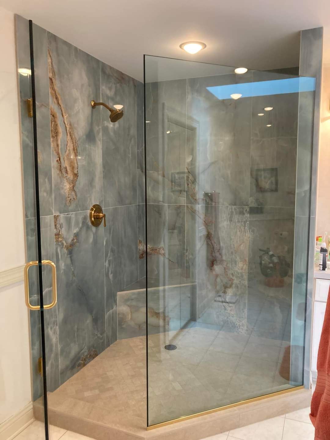 A bathroom with a walk in shower with a glass door.
