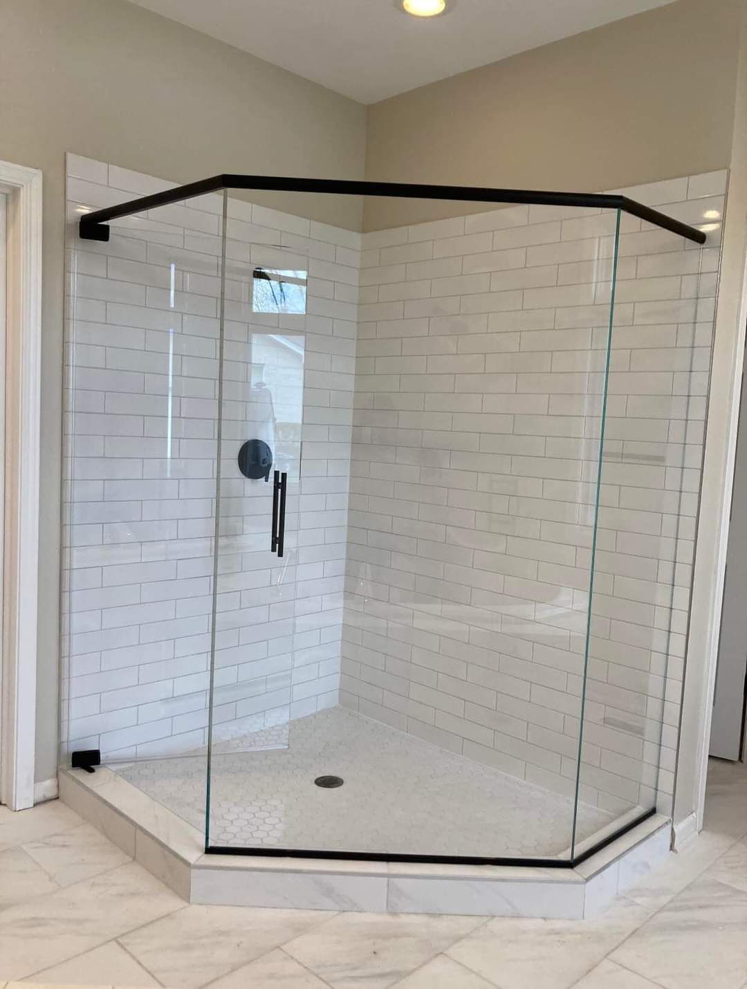 A bathroom with a walk in shower with a glass door and white brick walls.