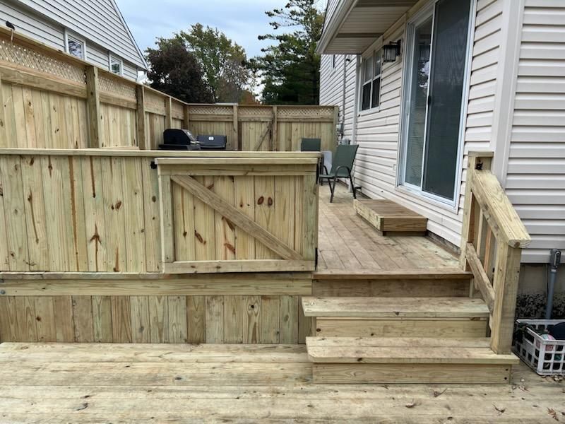 A wooden deck with stairs and a fence in front of a house.