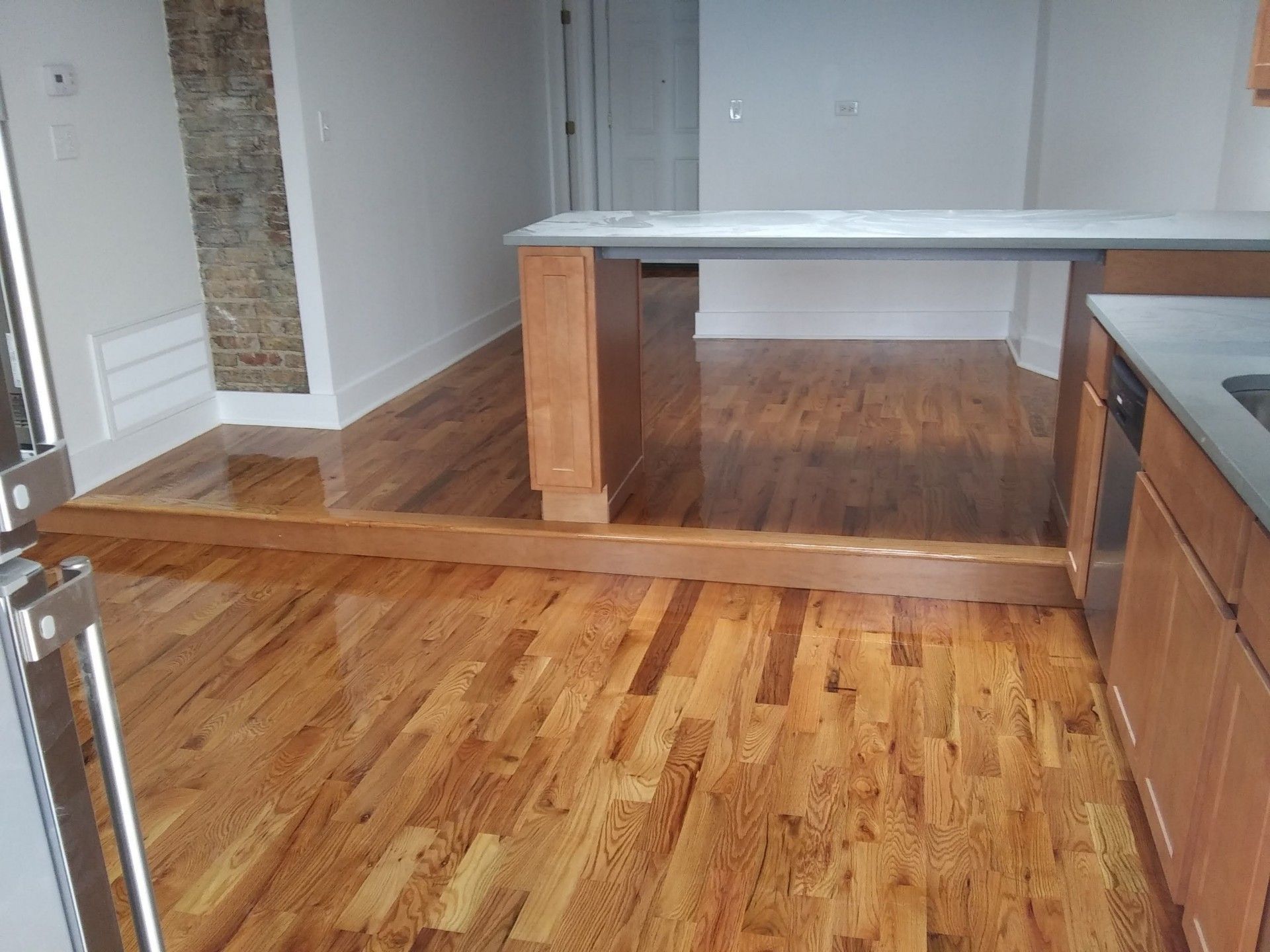 An empty kitchen with hardwood floors and a white counter top