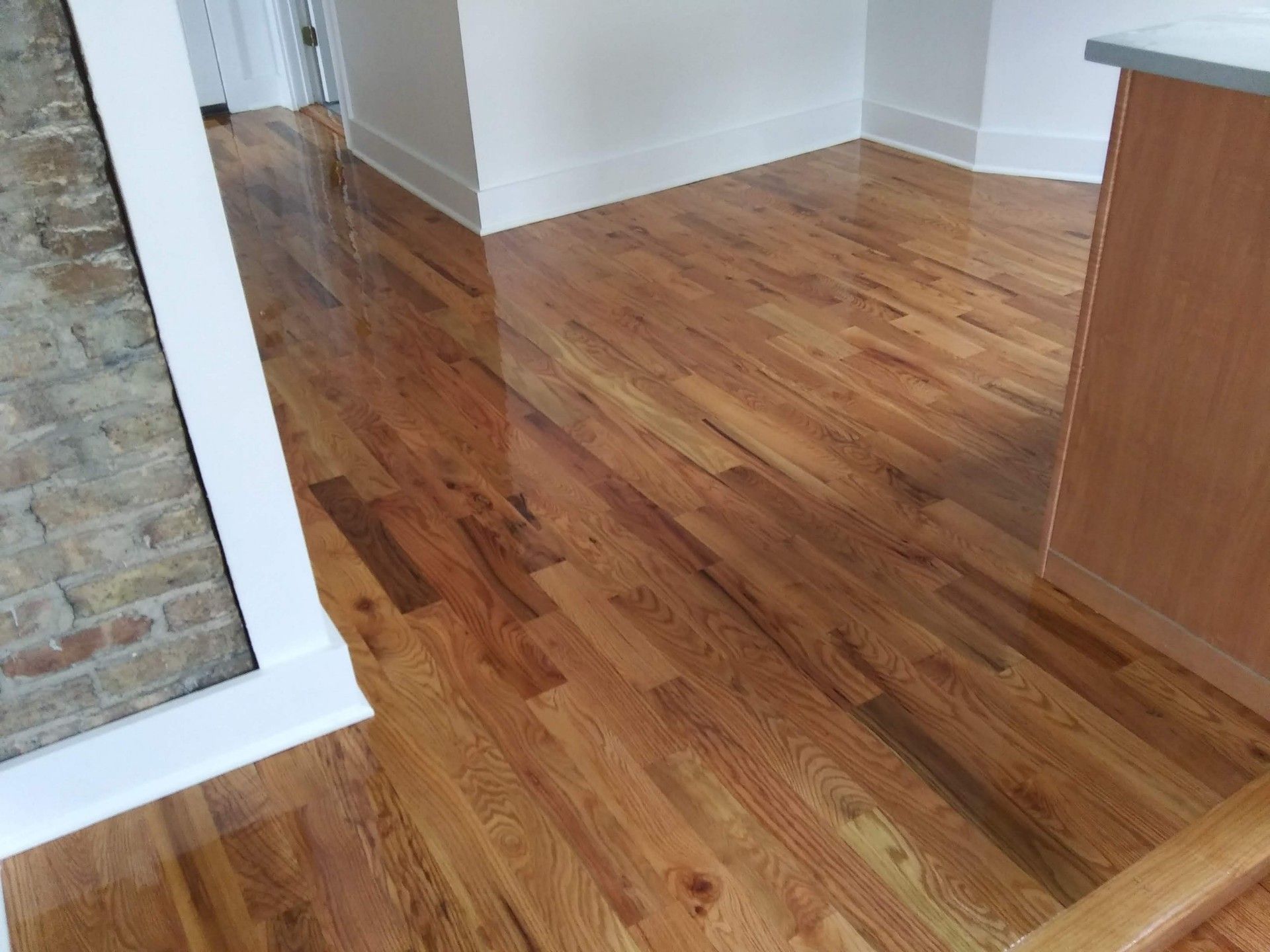 A kitchen with hardwood floors and a brick wall