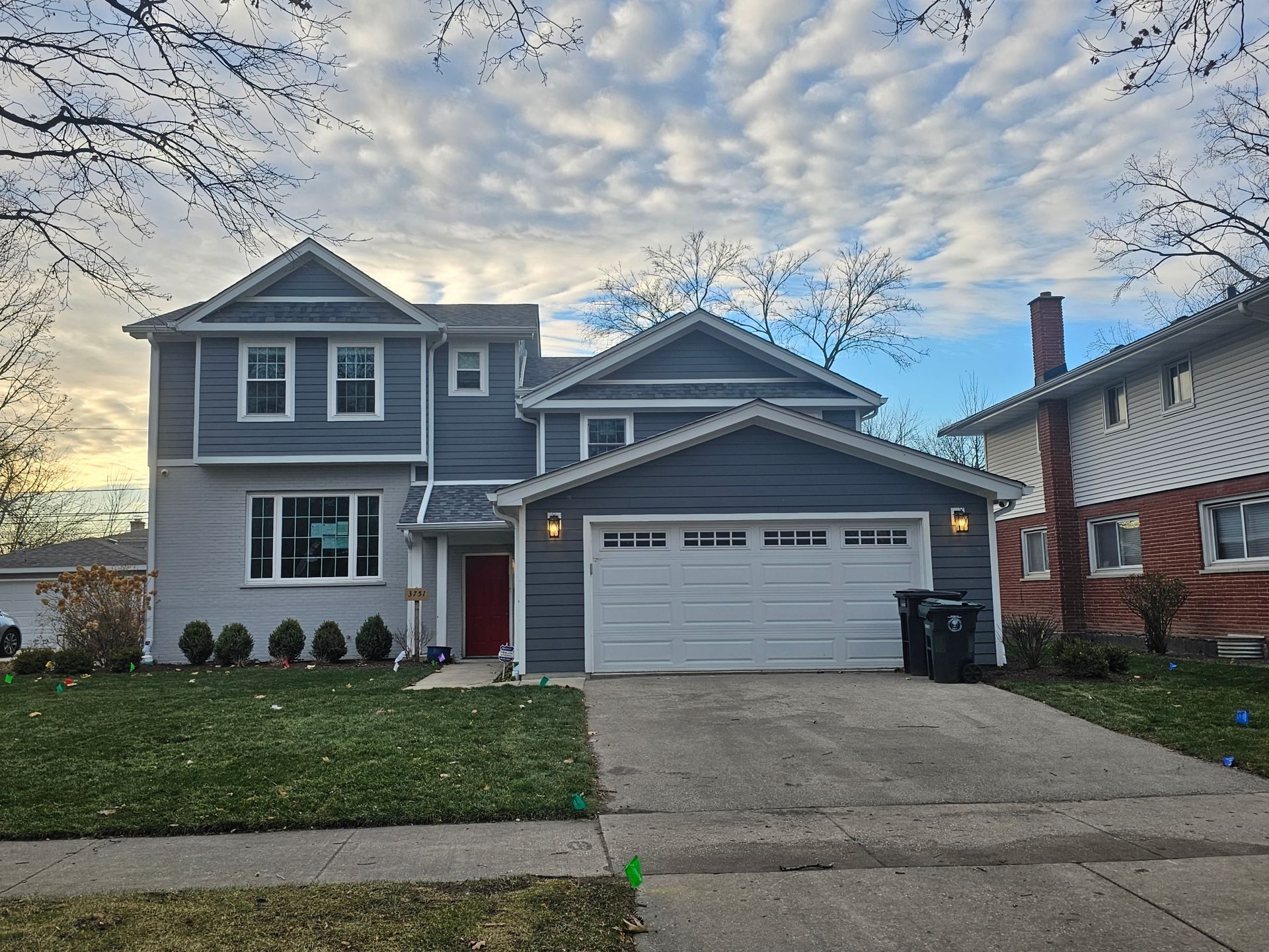 A large house with a white garage door and a brick house in the background.