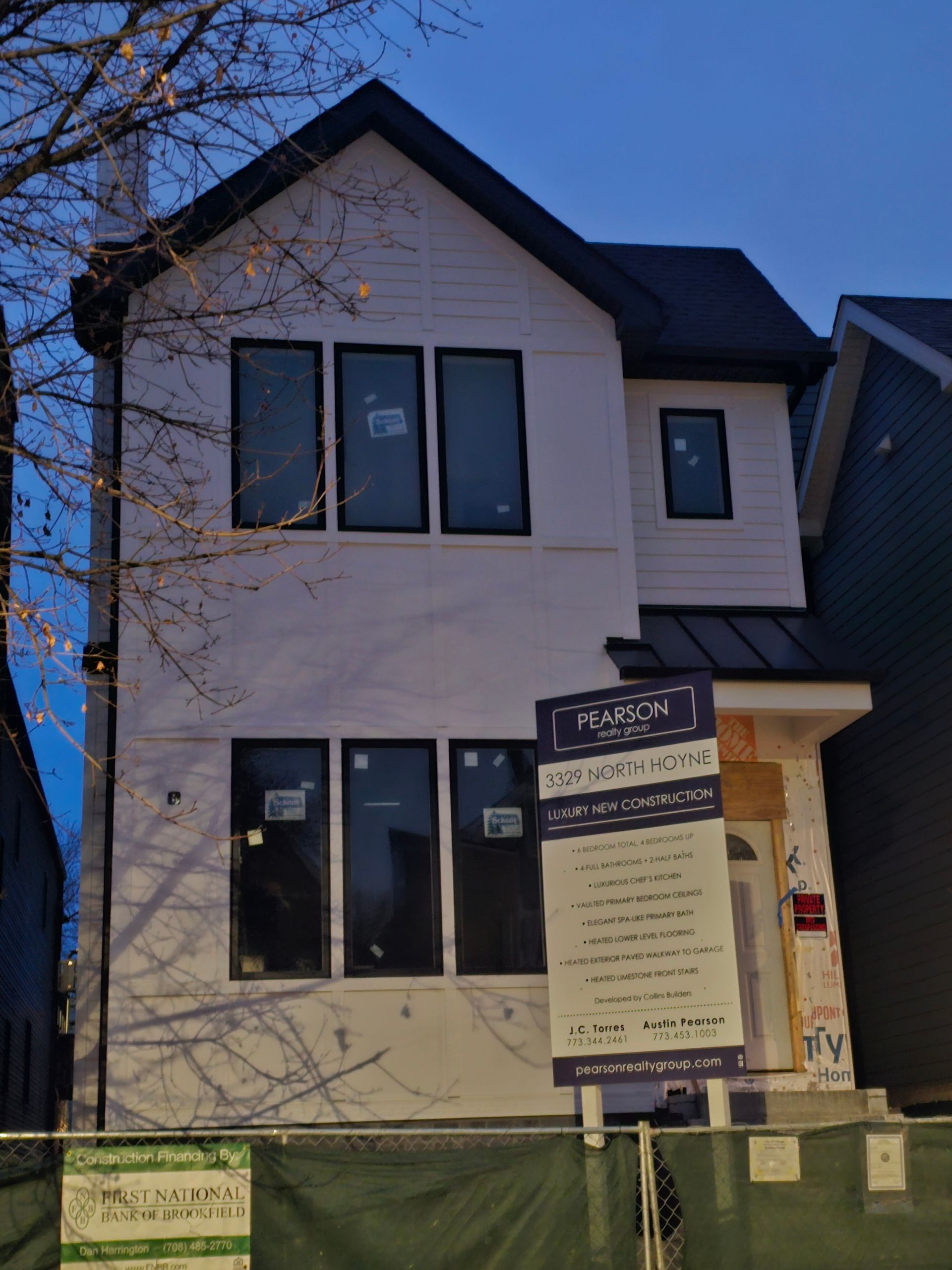 A white house with a black roof is under construction