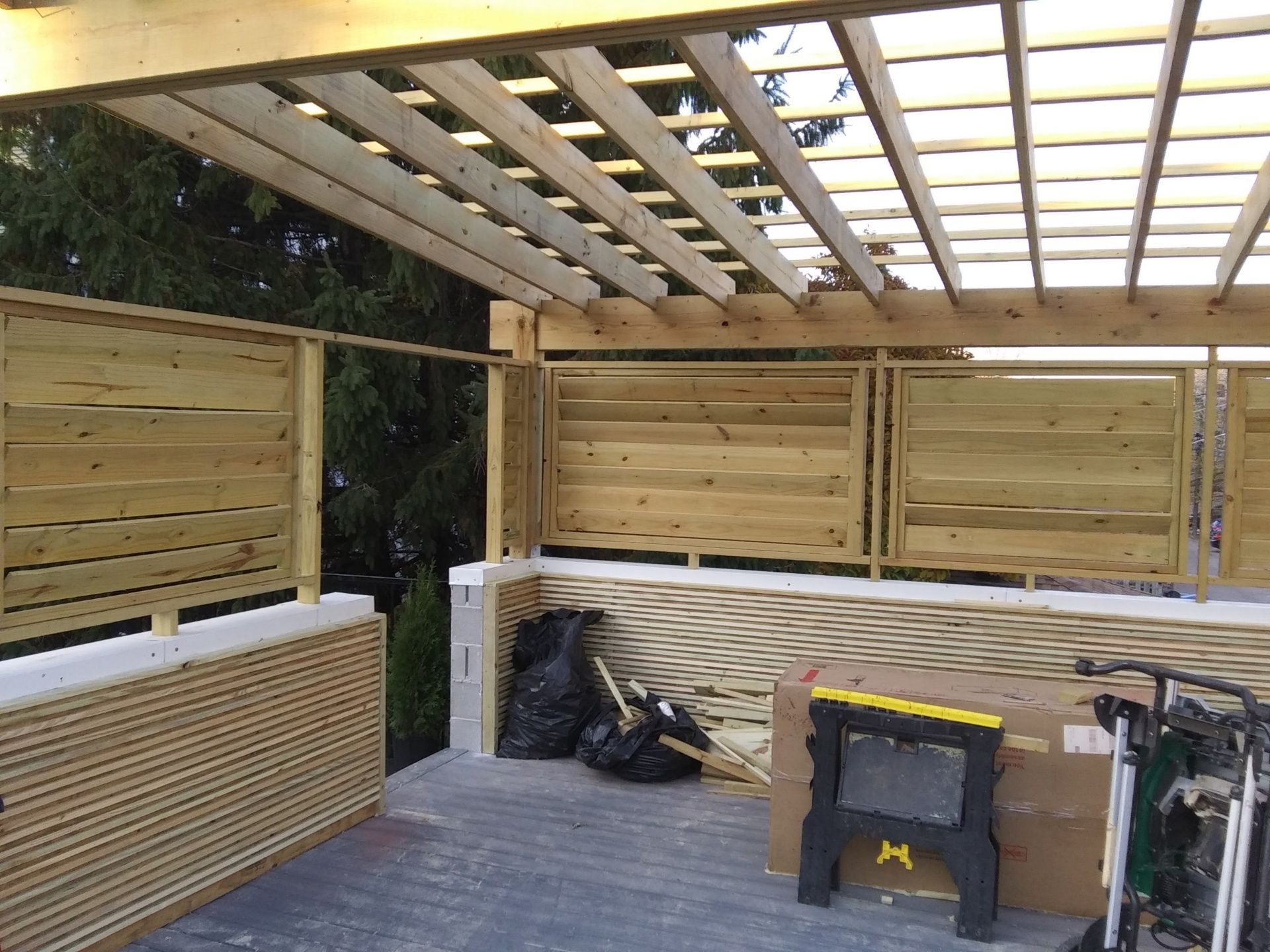 A wooden pergola is being built on top of a concrete deck.