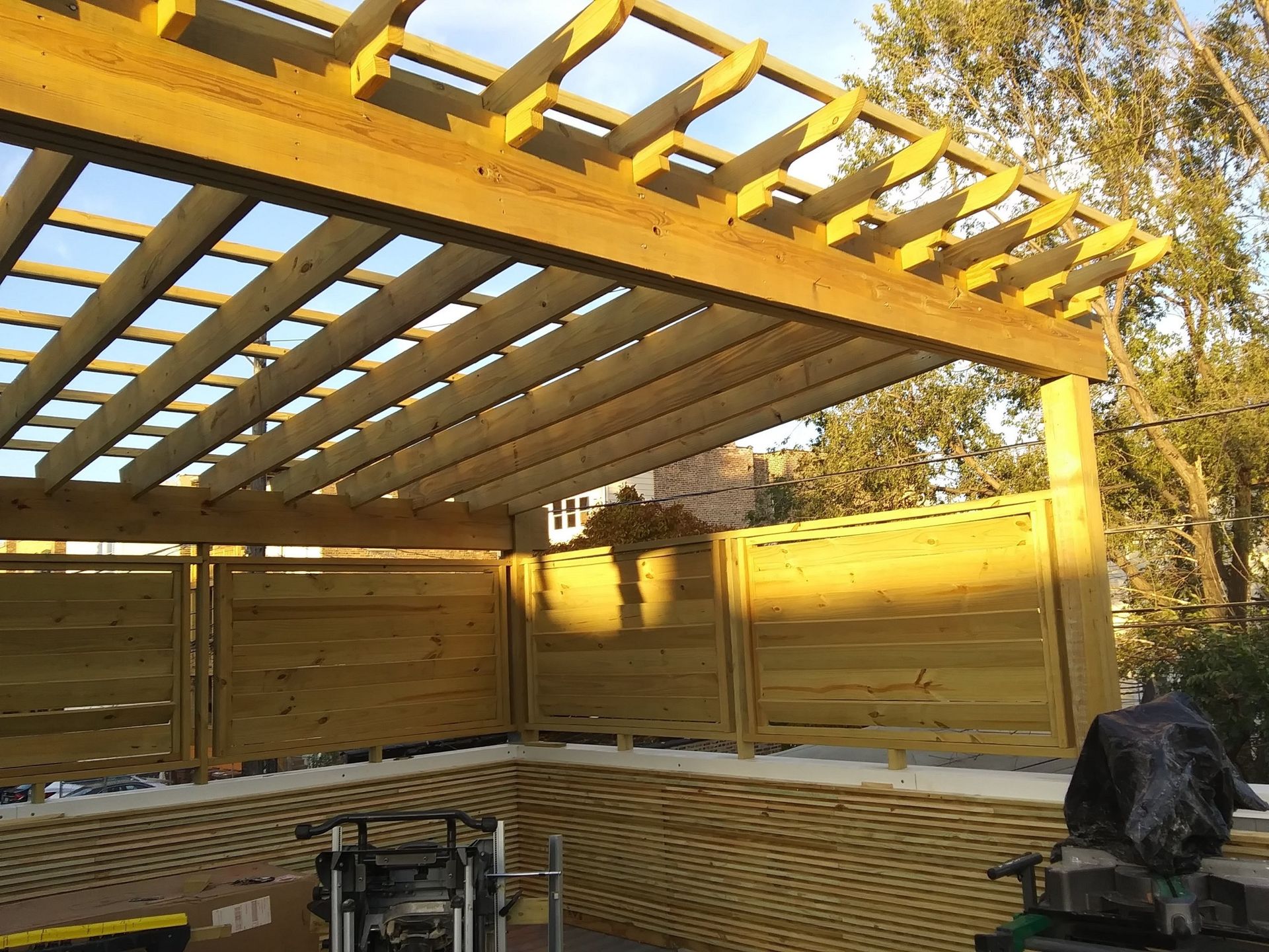 A wooden pergola is being built in a backyard.