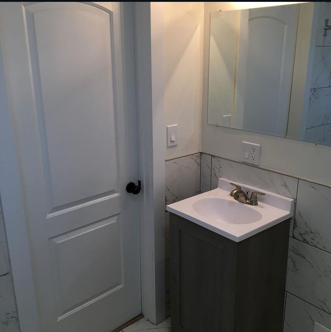A bathroom with a sink , mirror and door