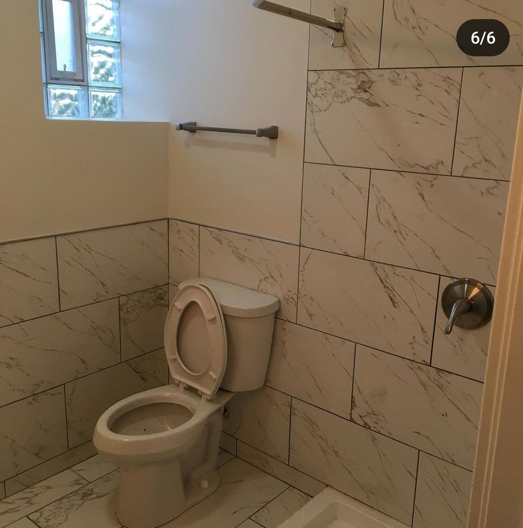 A bathroom with a toilet and a window with a sticker that says 6/6