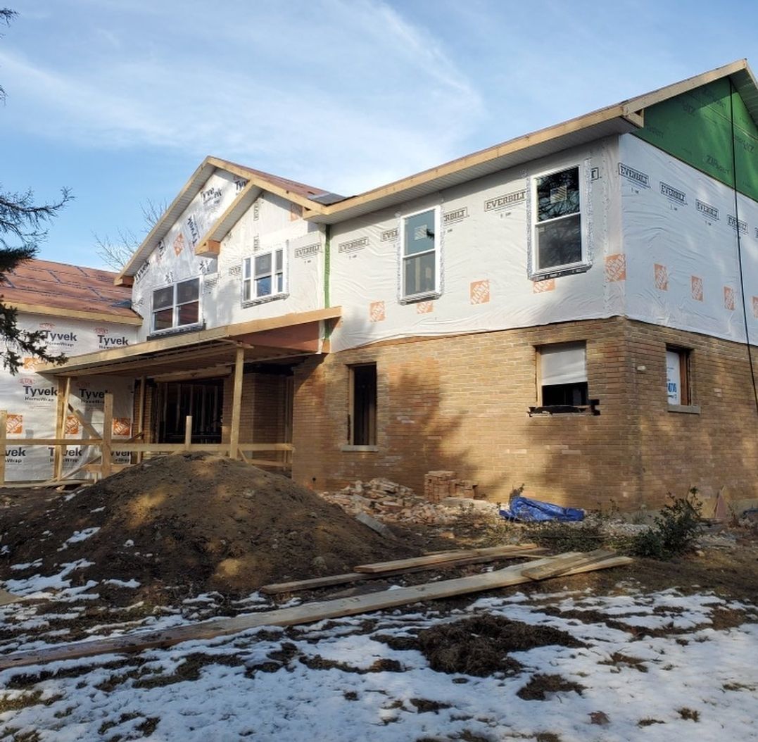 A large brick house is being built in the snow.