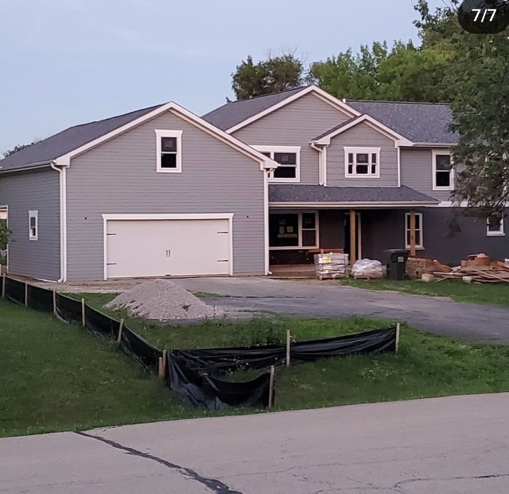 A large house with a garage and a fence in front of it.