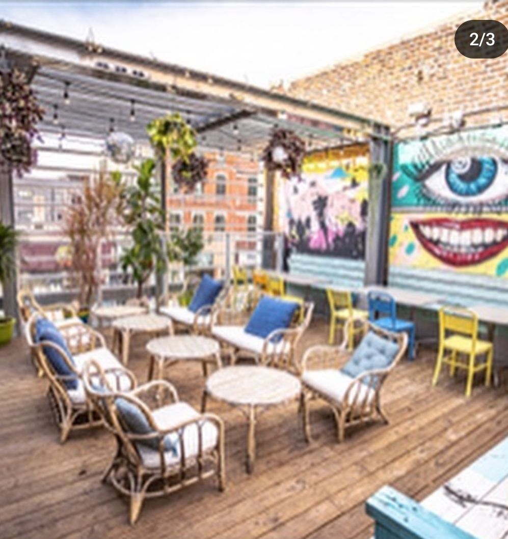 A patio with chairs tables and a painting of an eye on the wall