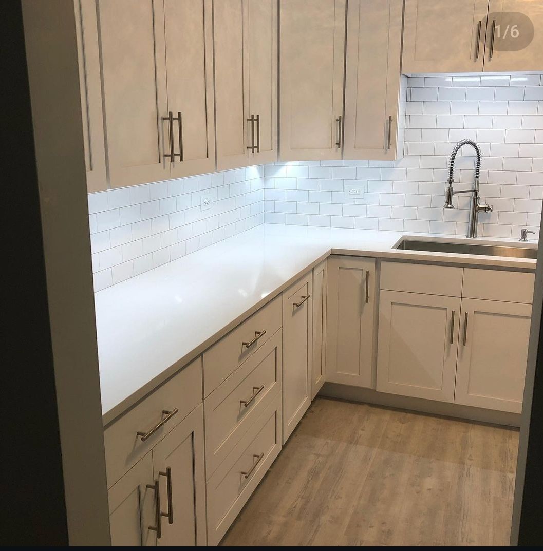A kitchen with white cabinets and white counter tops
