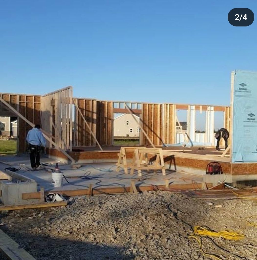 A man is standing in front of a house under construction.