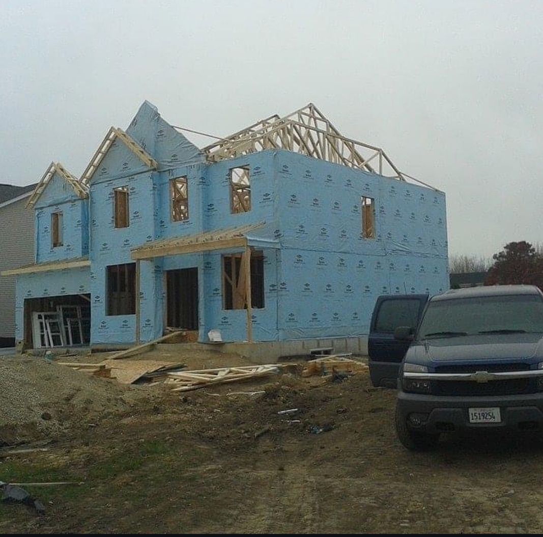 A blue house is being built with a van parked in front of it.