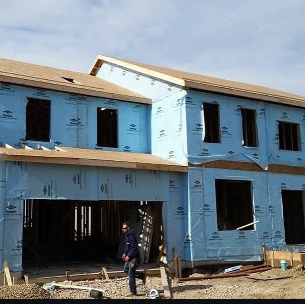 A man is standing in front of a house that is being built.