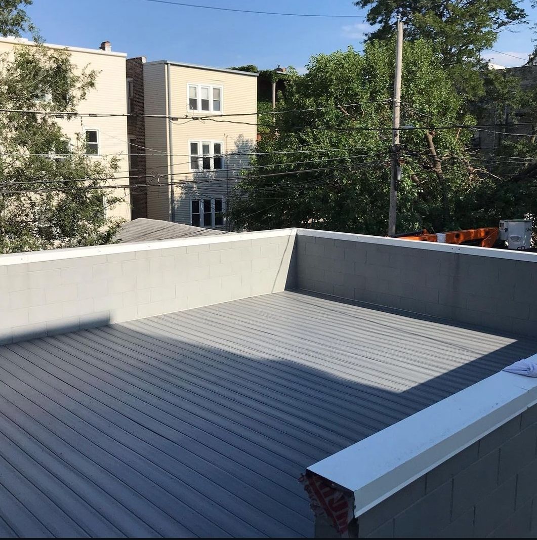 A rooftop deck with a view of a building and trees