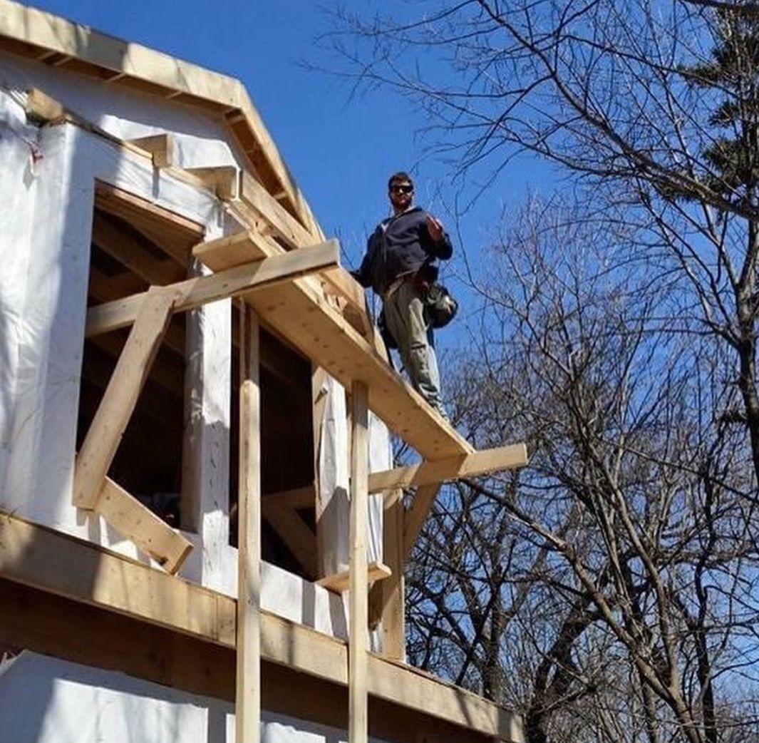 A man is standing on the roof of a building under construction
