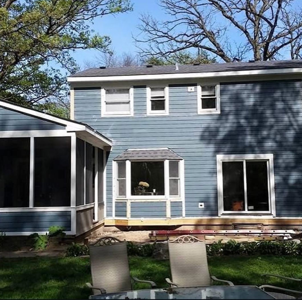 A blue house with white trim and a screened in porch