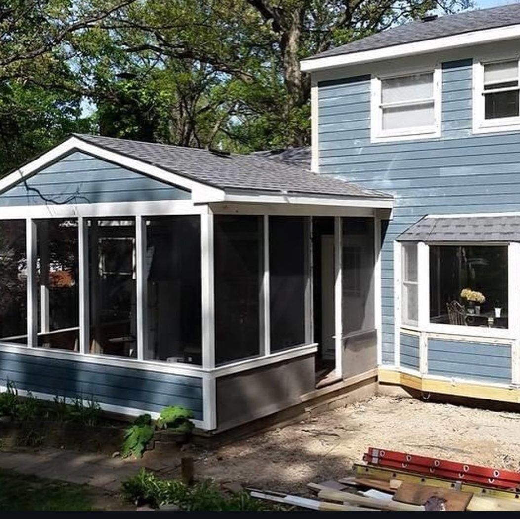 A blue house with a screened in porch and a ladder in front of it.