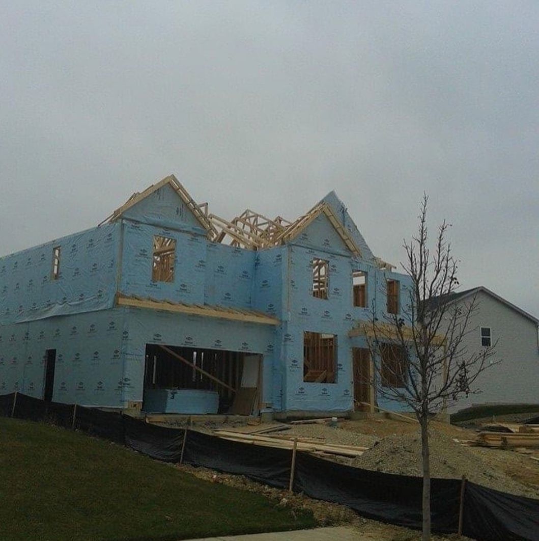 A large blue house is being built in a residential area.