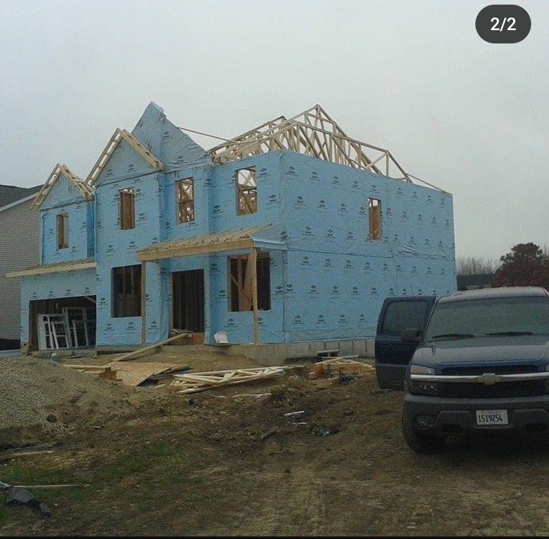 A blue house is being built with a truck parked in front of it.