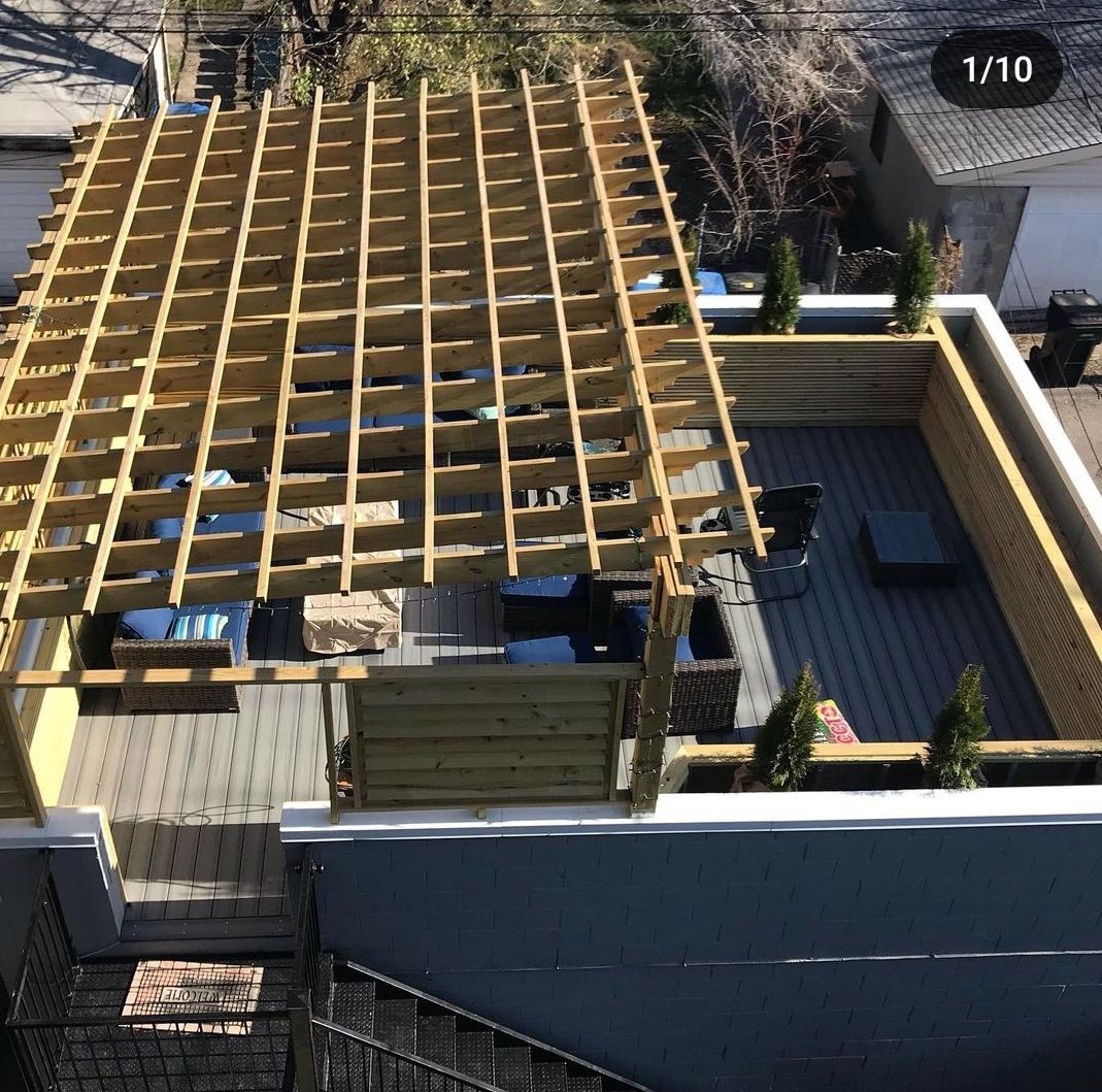 A rooftop deck with a wooden pergola on top of it