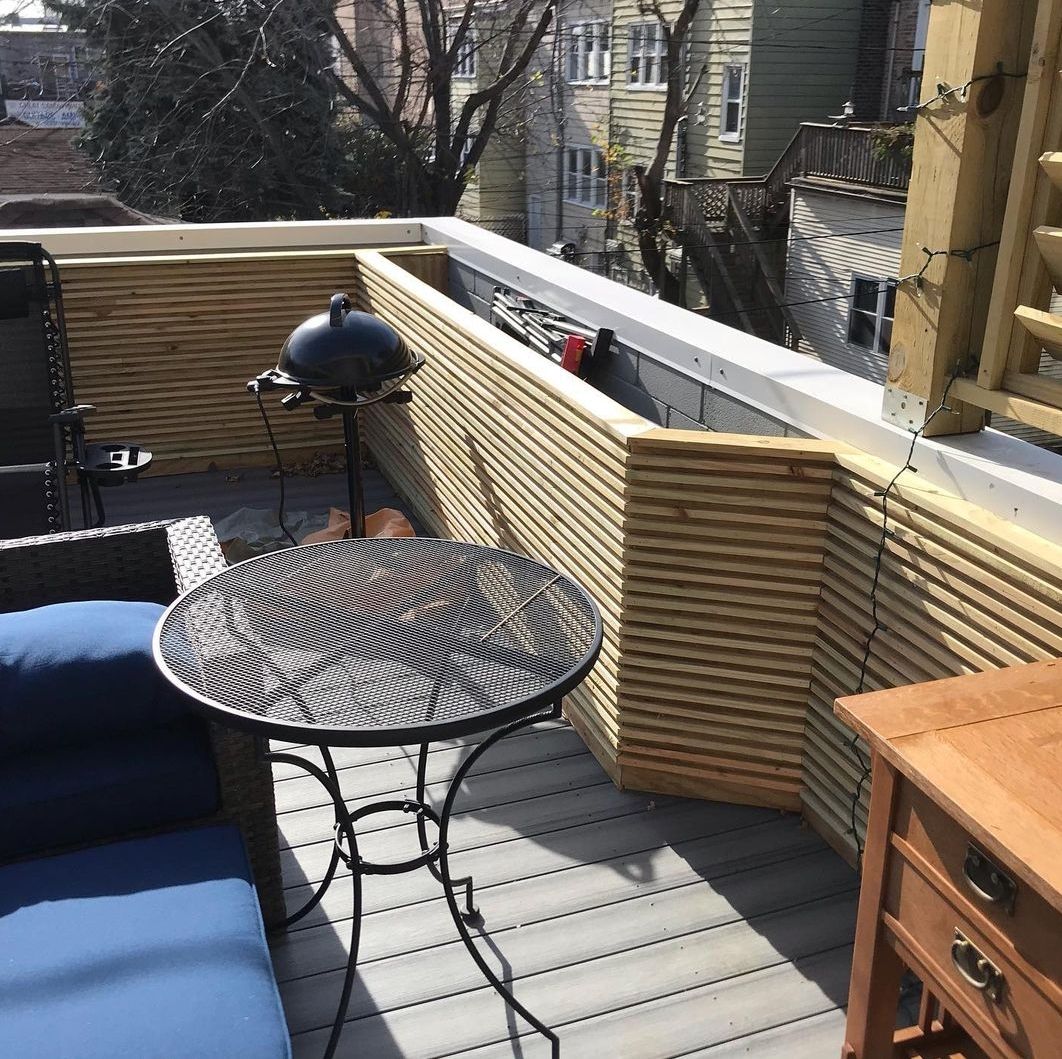 A balcony with a table and chairs and a grill