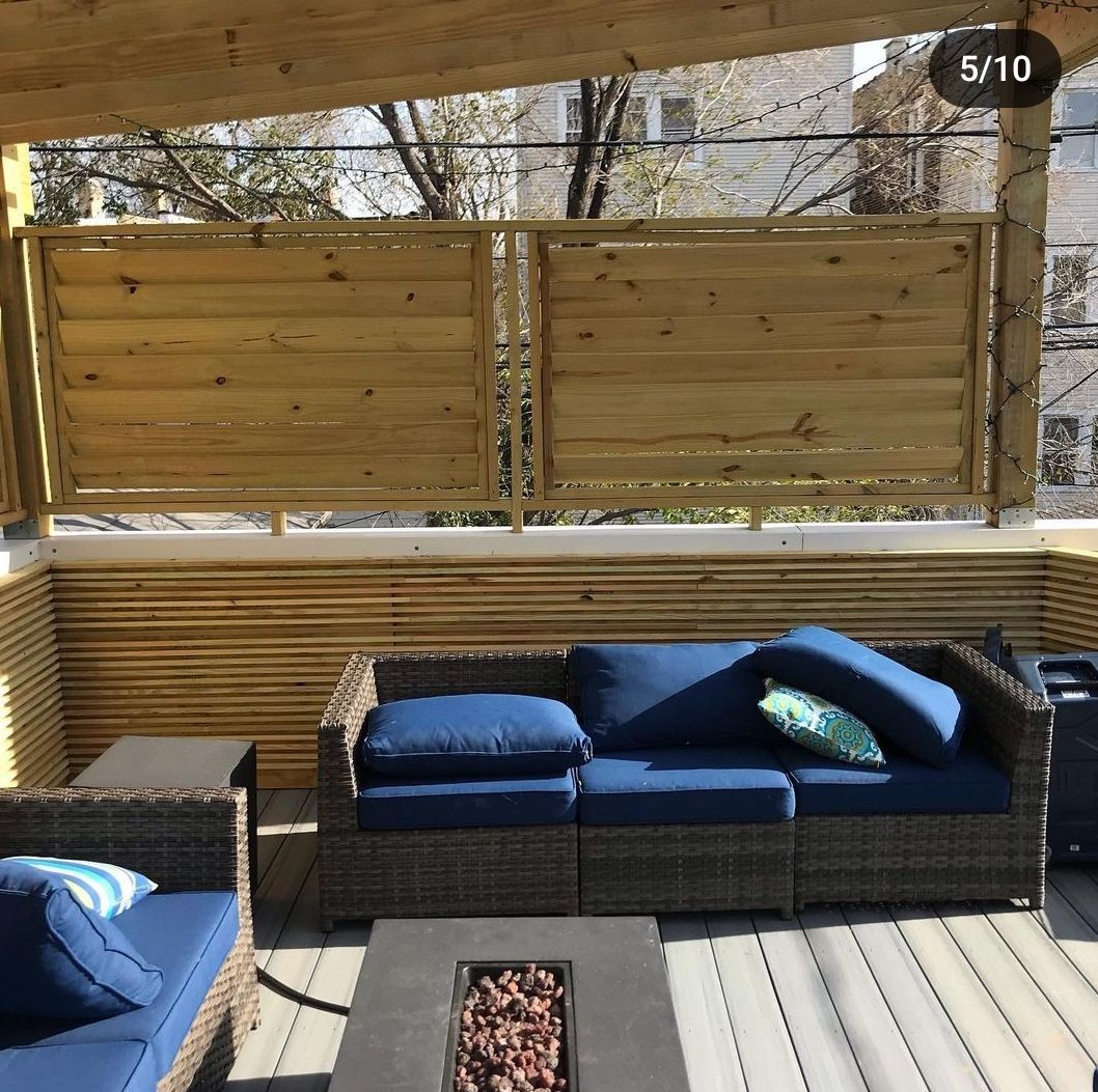 A patio with wicker furniture and a wooden fence