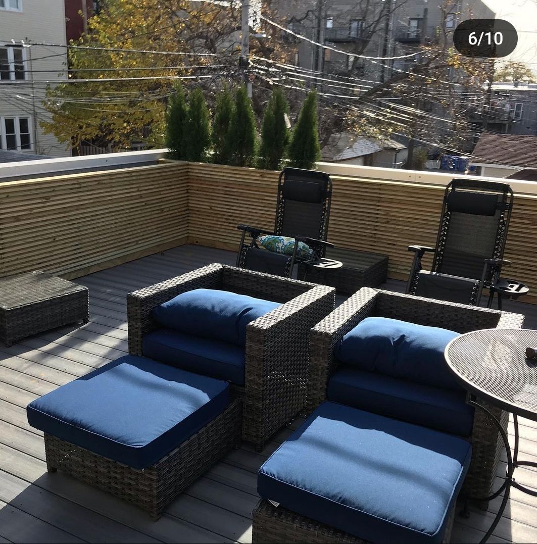 A patio with wicker chairs and ottomans with blue cushions