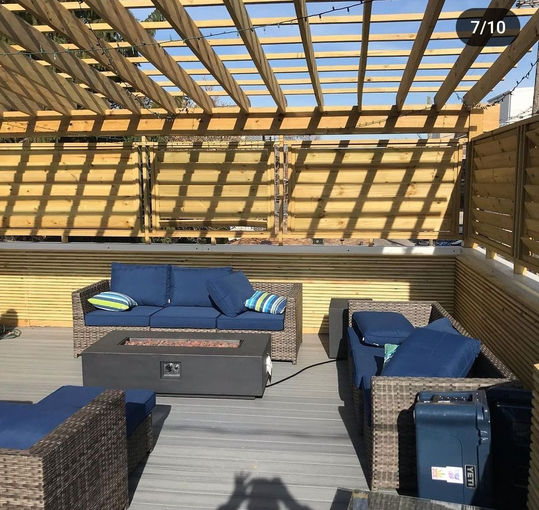 A patio with a couch and chairs under a wooden pergola