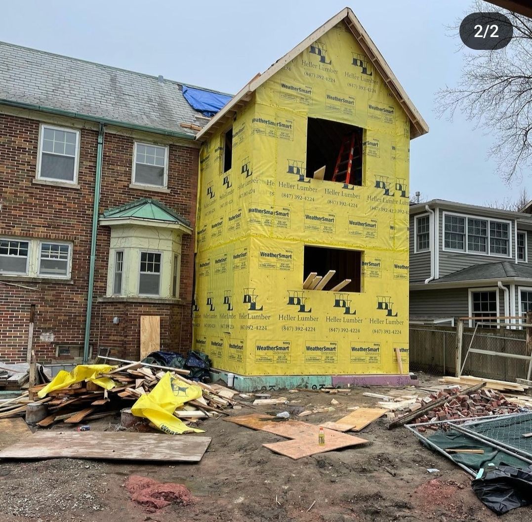 A brick house is being remodeled with yellow insulation