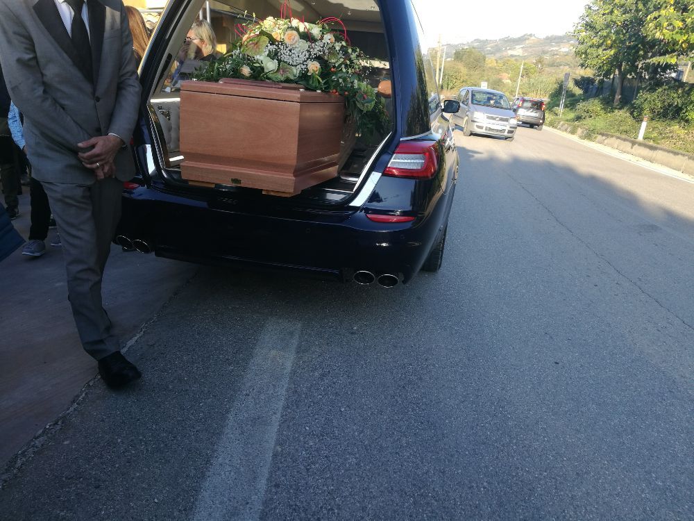 Feretro con addobbi floreali dentro carro funebre