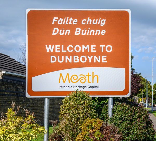 A brown welcome sign for Dunboyne, County Meath, featuring text in Irish and English with the Meath county logo.