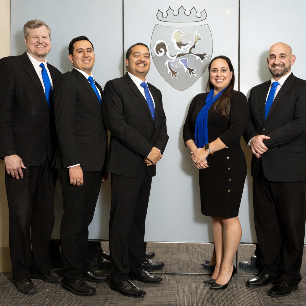 Five people in formal attire stand in front of a logo. Blue ties and accents.
