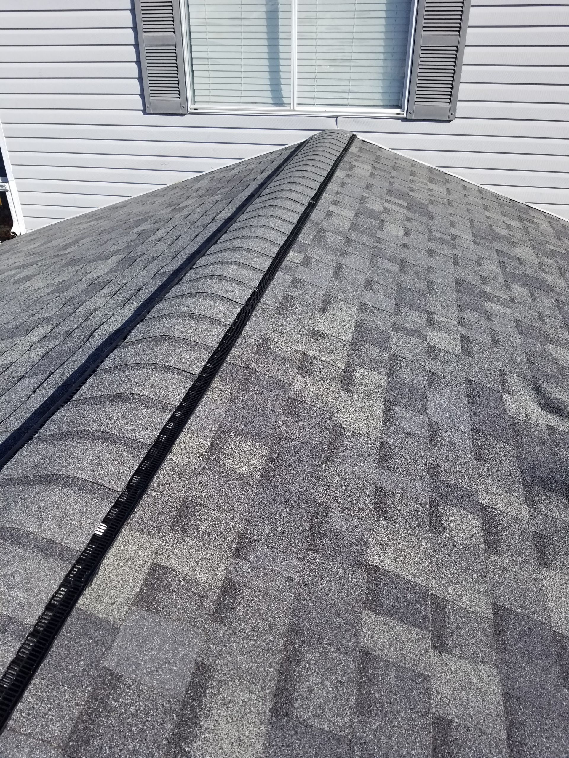 A close up of a roof with a window in the background.