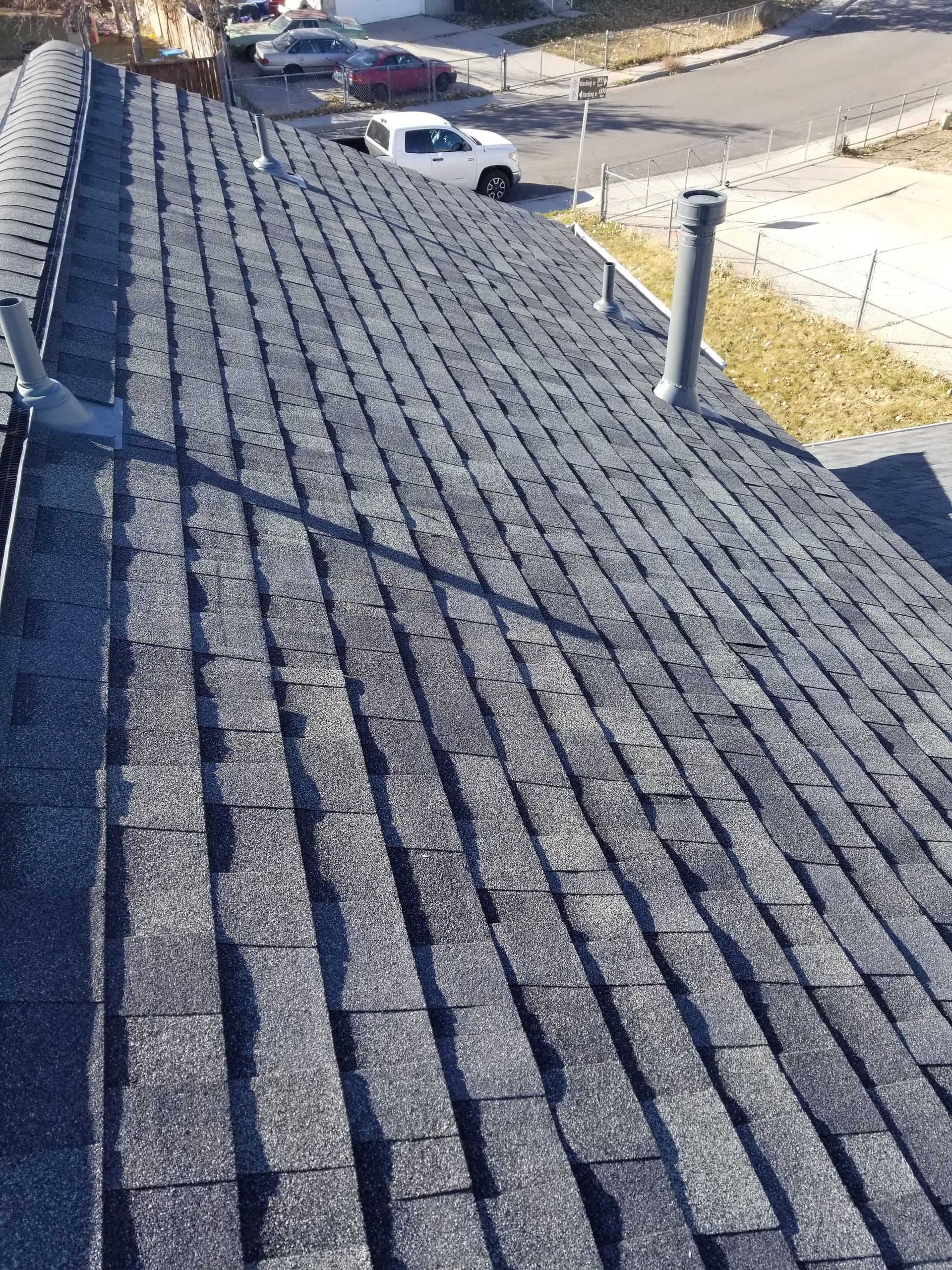 A roof with a lot of shingles and a white truck parked on it.