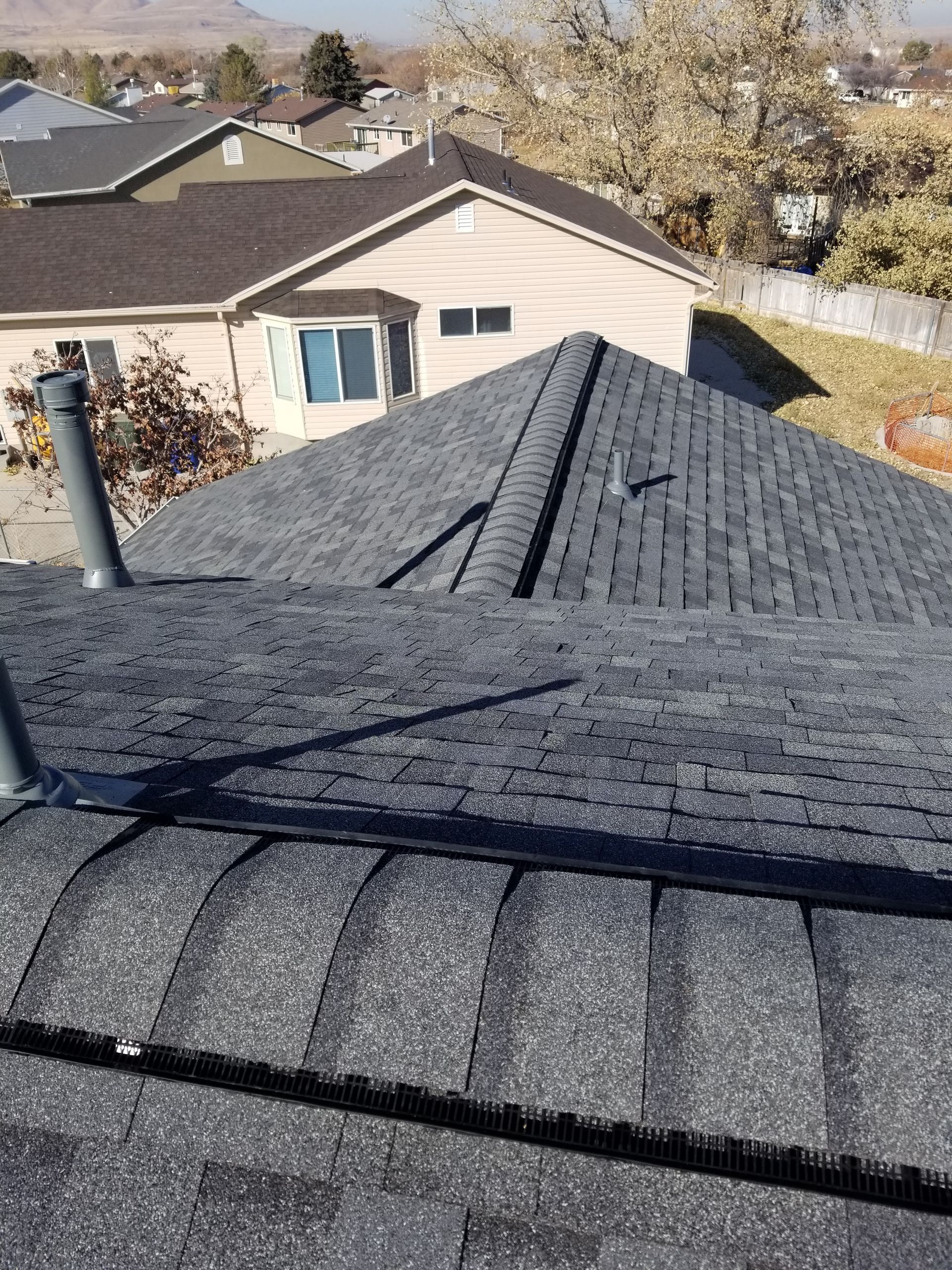 A roof with a chimney on it and a house in the background.
