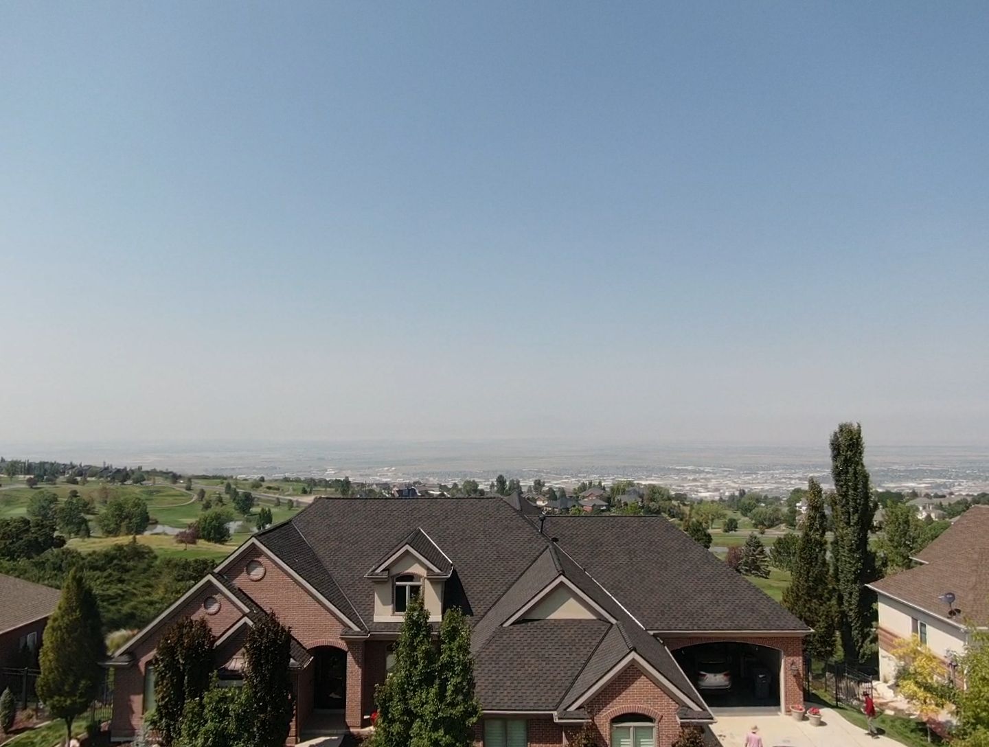 An aerial view of a large brick house with a view of a golf course.