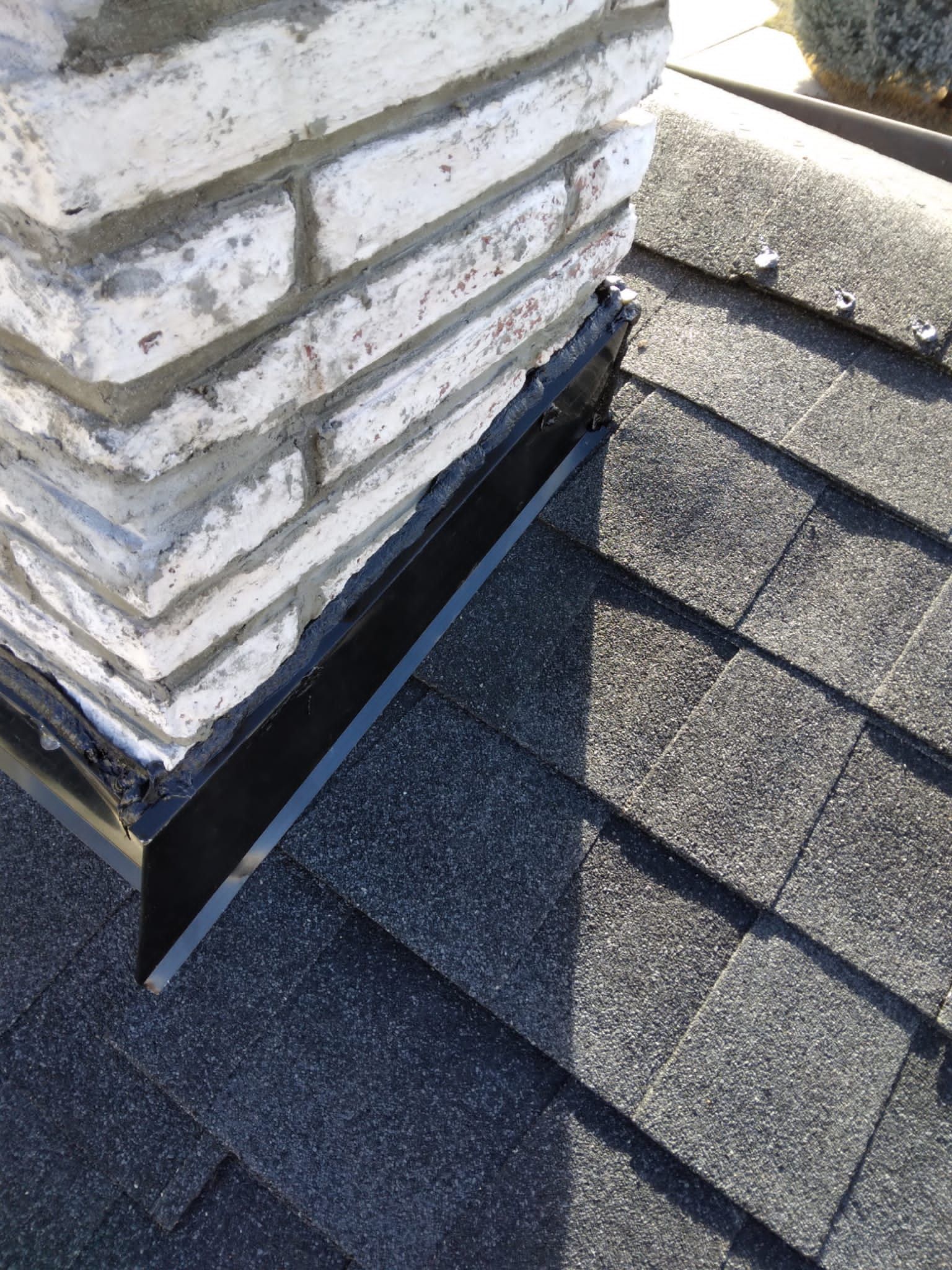 A chimney is sitting on top of a roof next to a brick wall.