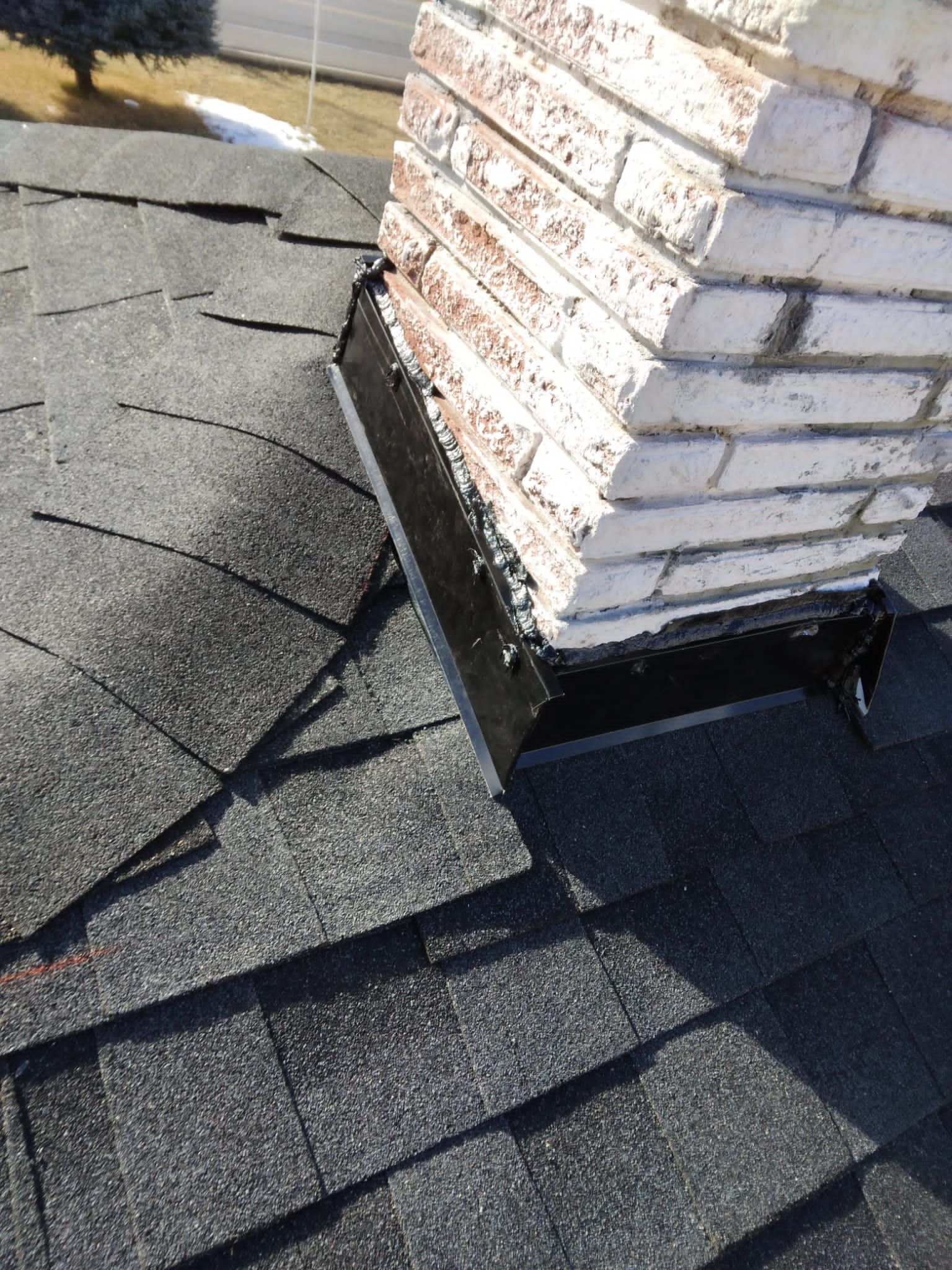 A chimney is sitting on top of a roof next to a brick wall.