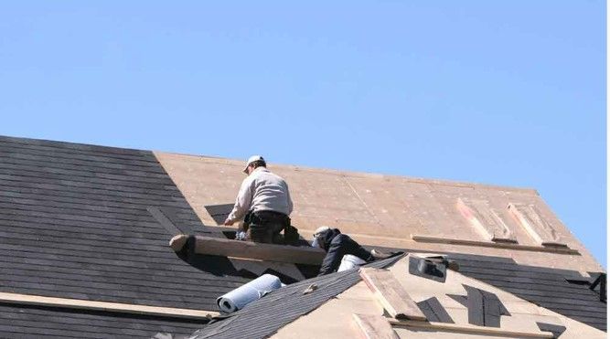 Two men are working on the roof of a house.