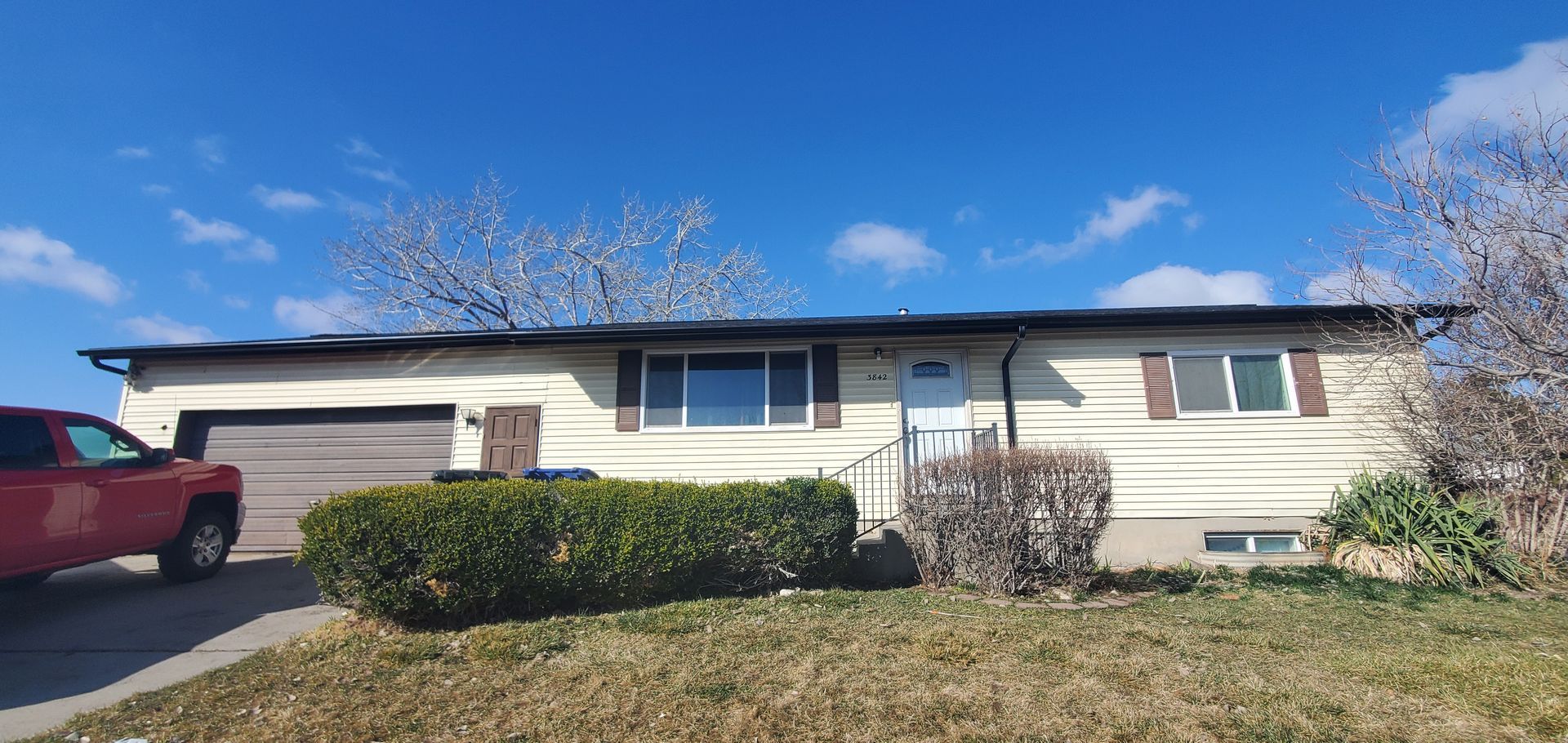 A red truck is parked in front of a white house.