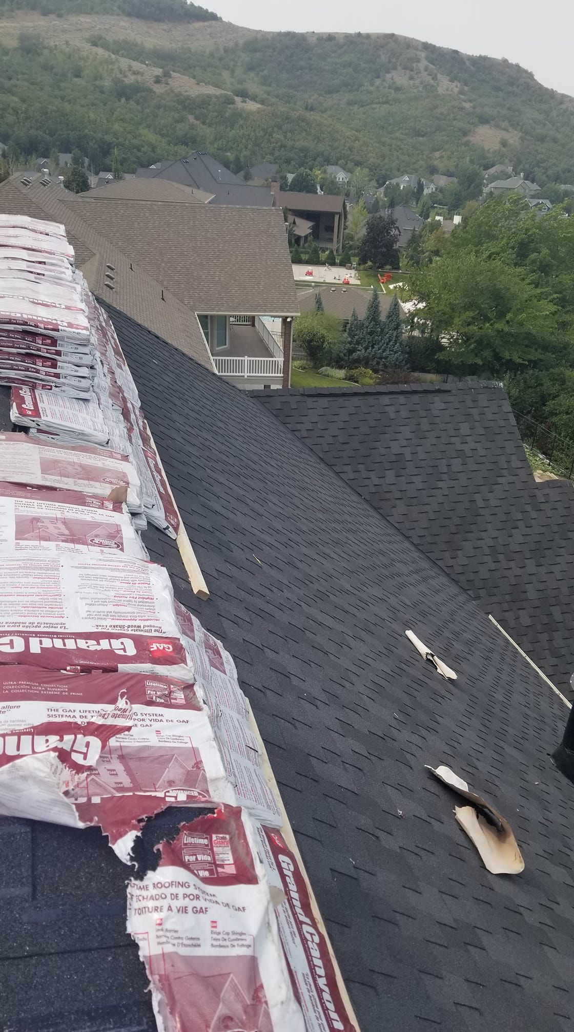 A roof is being installed on a house with a mountain in the background.
