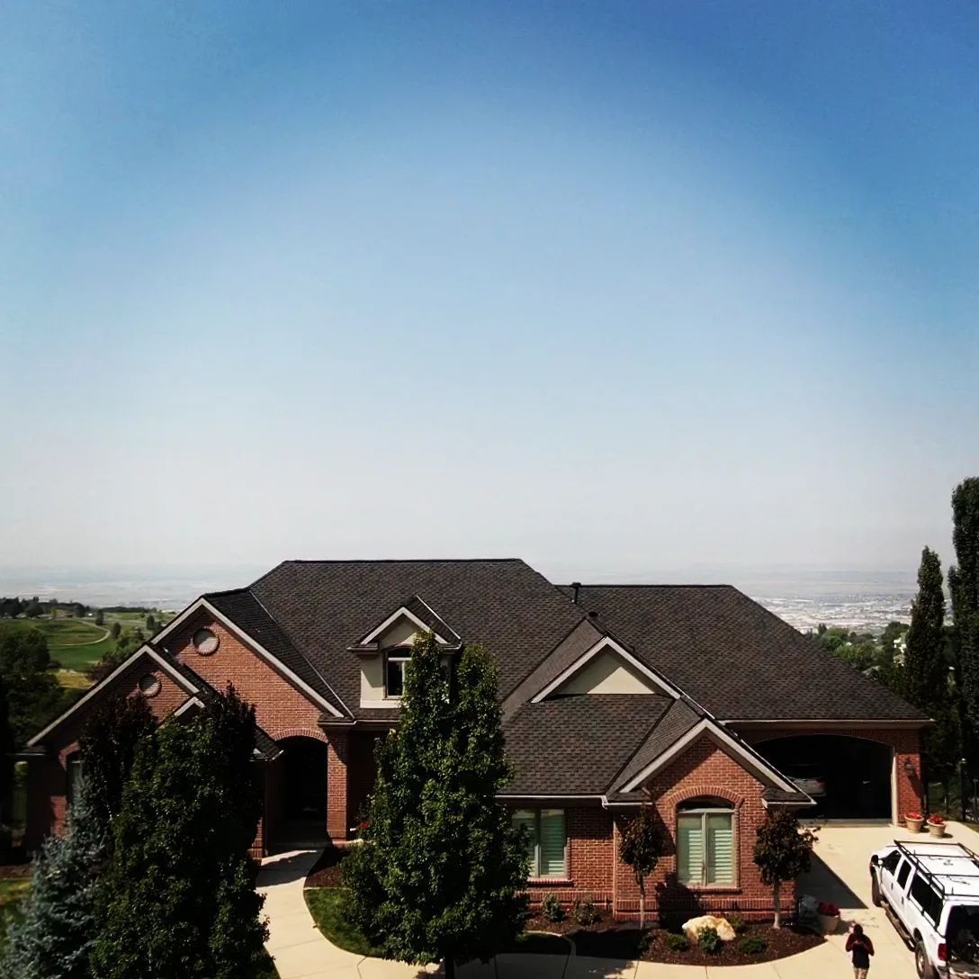 An aerial view of a large brick house with a black roof